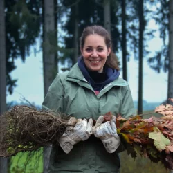 Eine Kollegin beim Tragen von Setzlingen